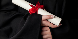 Certificate A rolled document with red bow is held by hands.